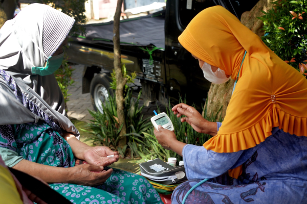 Two women use a glucometer in Indonesia 