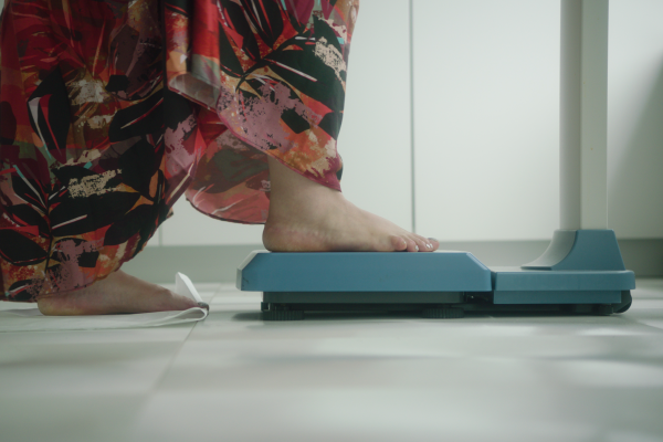 Woman steps onto a weighing scale 