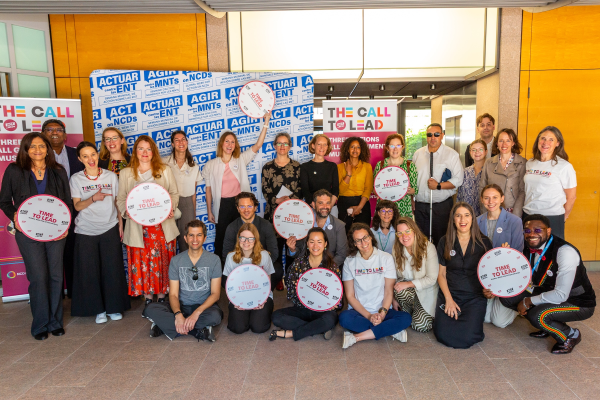 NCD advocates gather for a picture holding "Time to Lead" banners