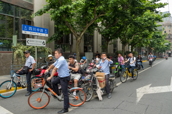 Men riding biclycles in a busy road in Shanghai 