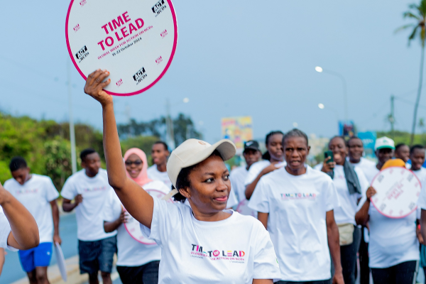 Tanzania NCDA advocate holding a "Time to Lead" clock during a Global Week for Action event in Dar es Salaam, Tanzania